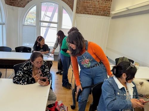 Valentina Ocampo Beltrán leaning over to assist a participant during a community embroidery workshop at The Women’s Building.