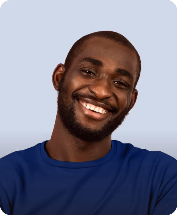 Smiling young man with a beard wearing a blue shirt against a light gray background.