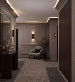 Cozy, modern hallway with a gray armchair, wall sconces, and pampas grass in a dark wooden side table.