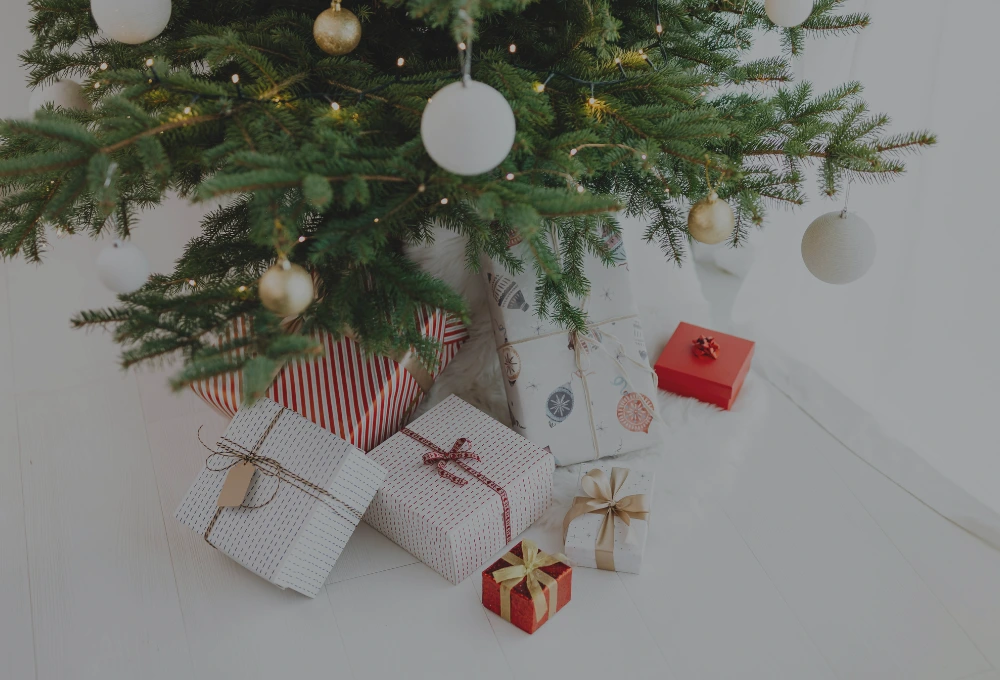 En gran med vit och röda julklappar under.