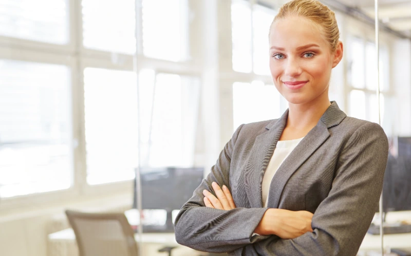 En blond kvinna i grå kavaj med armarna i kors.