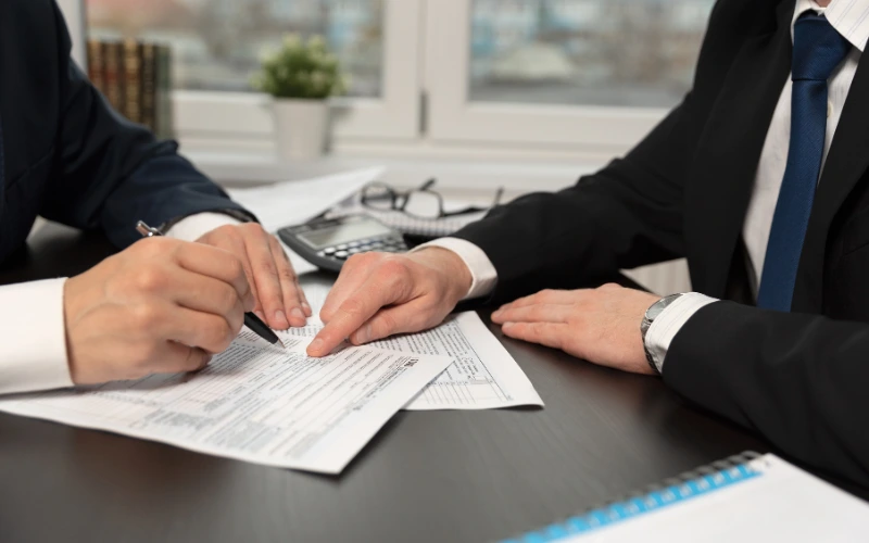 En person som håller i en penna med skattedokument och en miniräknare.