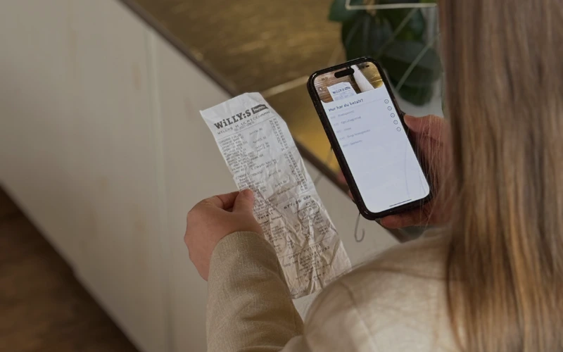 Kvinna som bokför ett kvitto med mobilen 