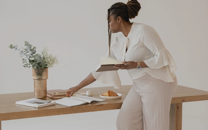 Kvinna med ljus klädsel som sitter på ett bord med papper framför sig 