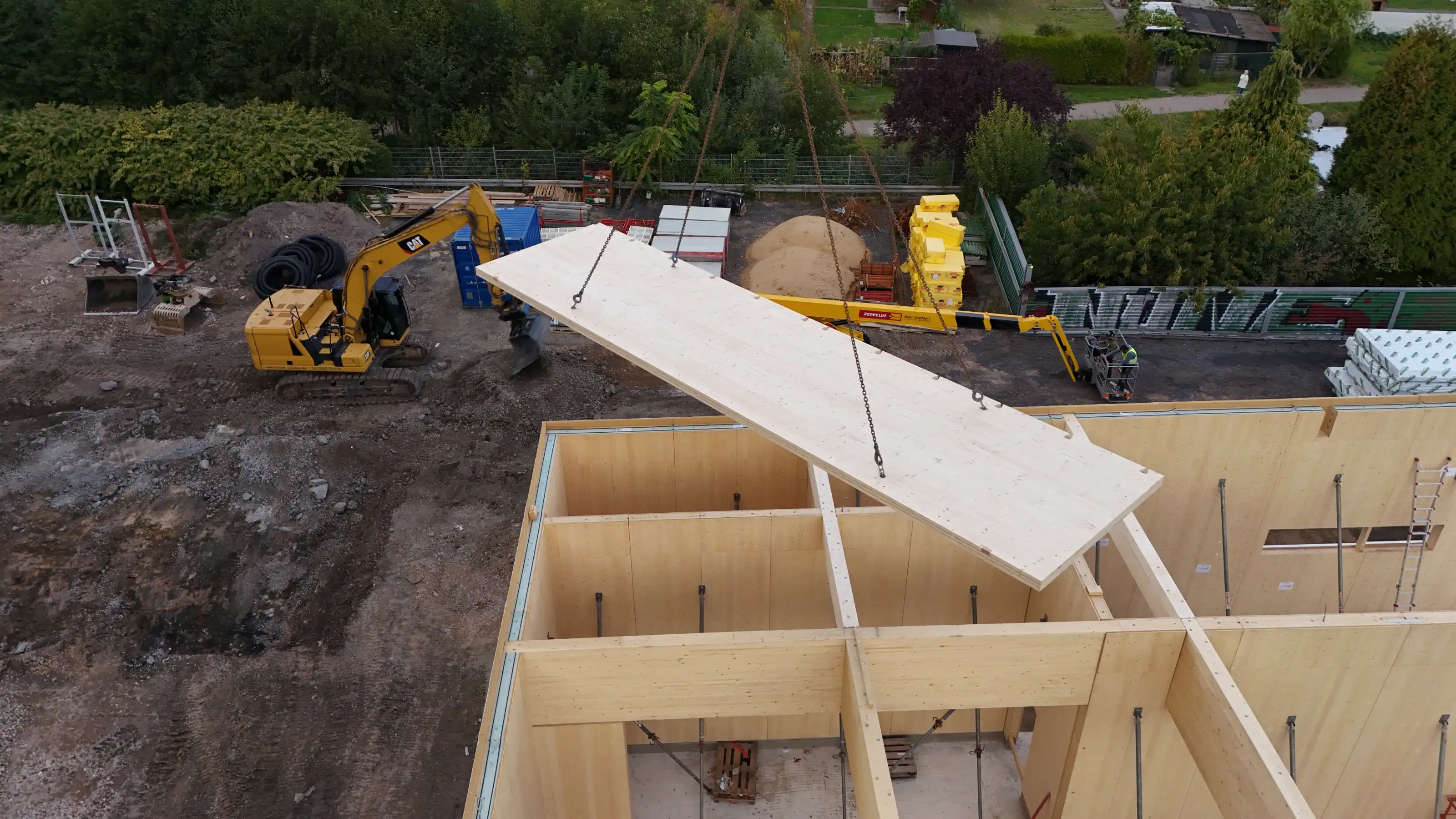 Luftaufnahme Pilotprojekt smartbuild - Kran hebt vorgefertigtes Holzmodul