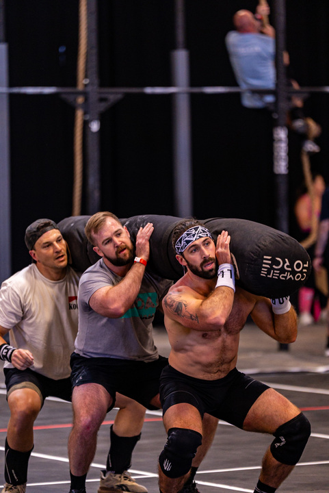 Team of CrossFitters carrying weighted bag