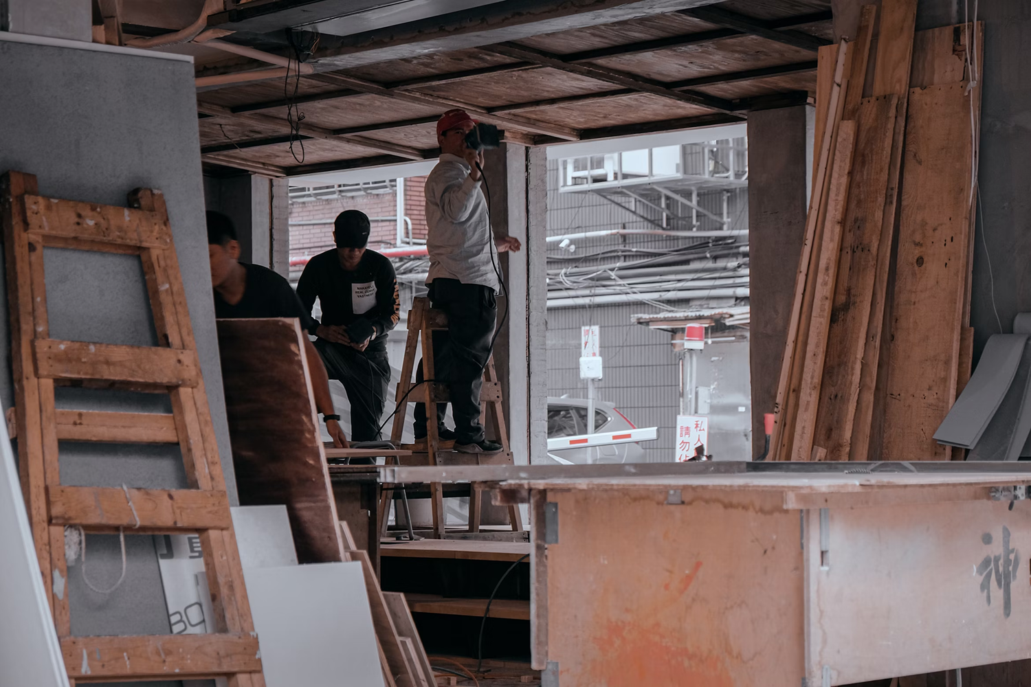 A bad contractor standing beside a wooden table, looking serious and uncertain indoors