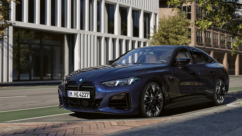 BMW i4 in Blau auf urbaner Straße mit moderner Architektur im Hintergrund – BMW Köhler in Karlstadt