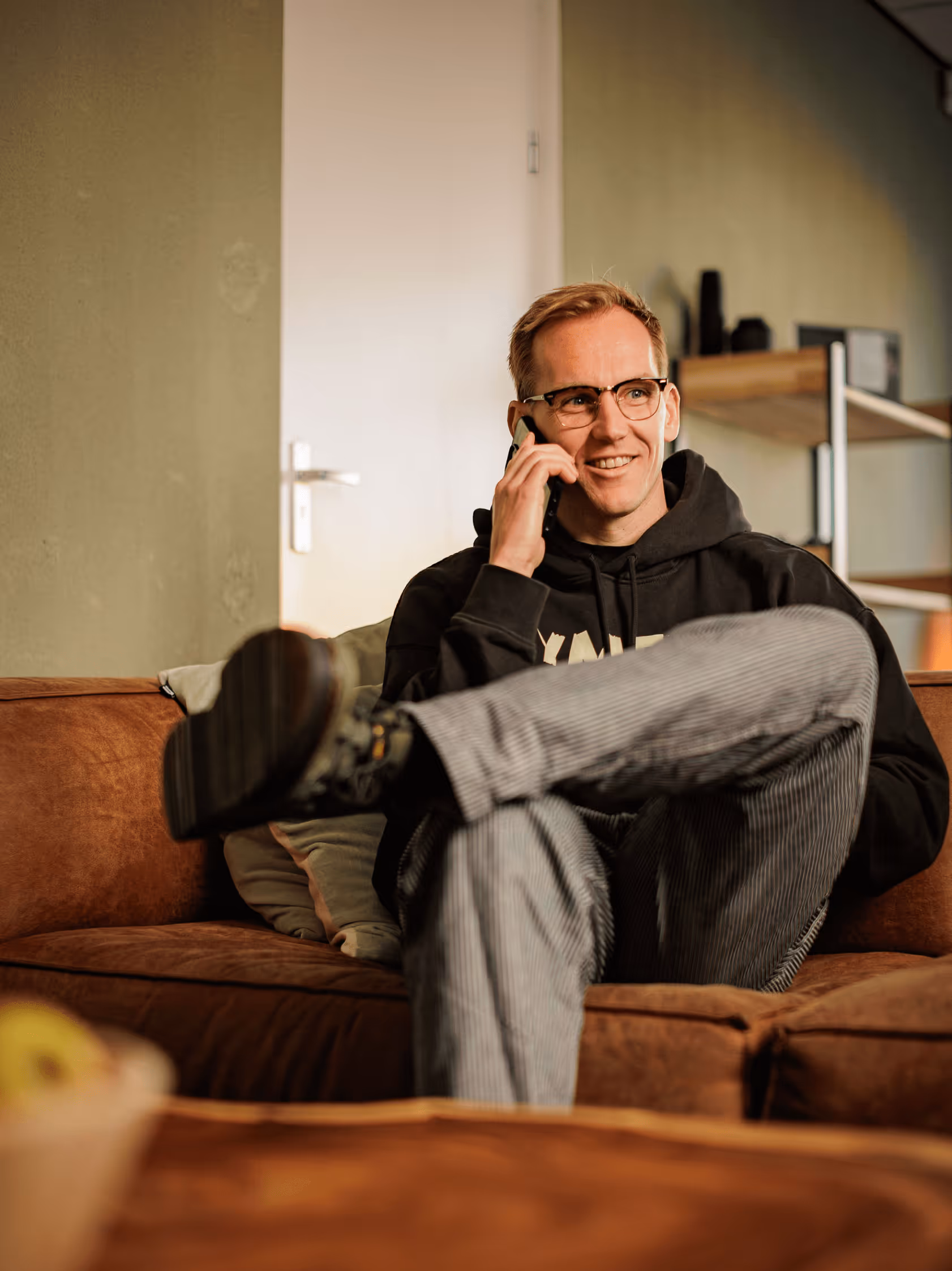 Sebastian van Gymful aan de telefoon in ontvangstruimte zittend op een bank