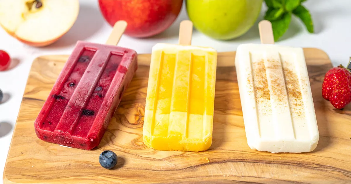 Drei verschiedene Hüttenkäse-Popsicles: mit Beeren, tropischen Früchten und Apfel-Zimt, dekoriert mit frischen Zutaten.