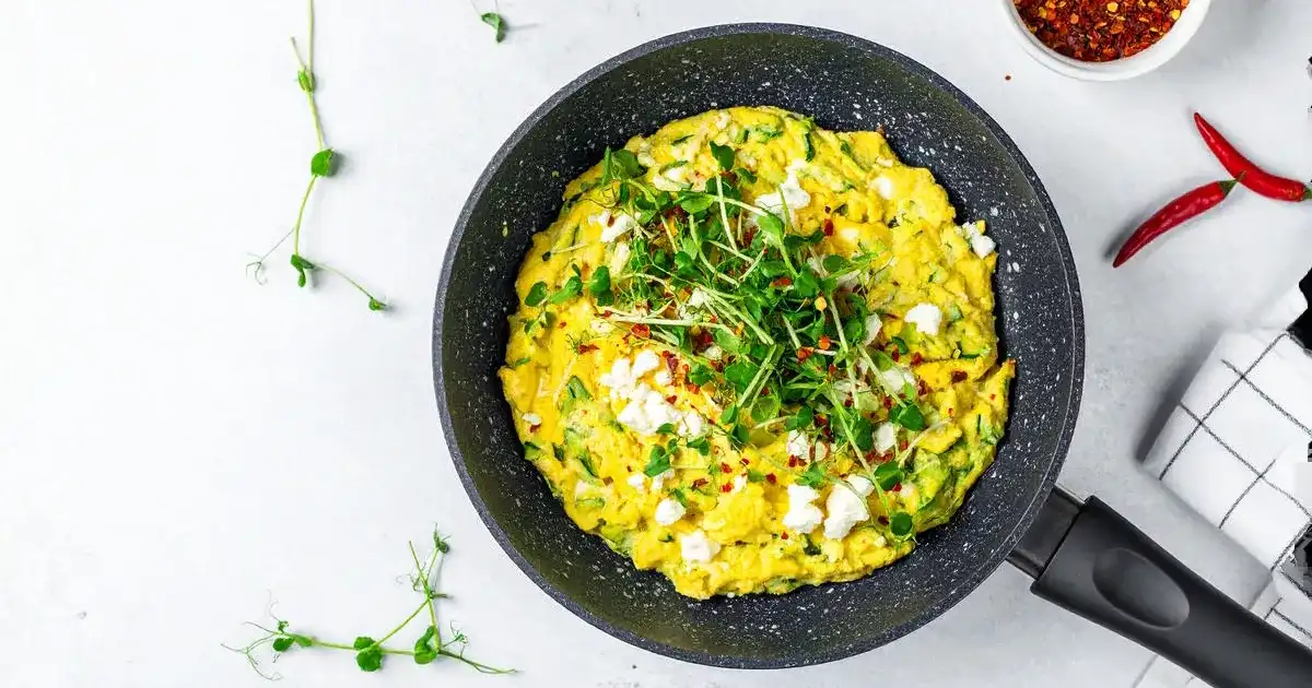 Proteinreiches Frühstück mit Rührei, Zucchini und Hüttenkäse in einer Pfanne serviert