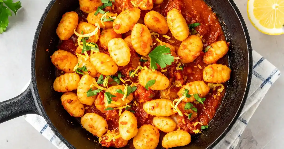 Knusprig gebratene Tofu-Gnocchi mit Chili-Tomatensoße und Zitronenkräutern in Pfanne