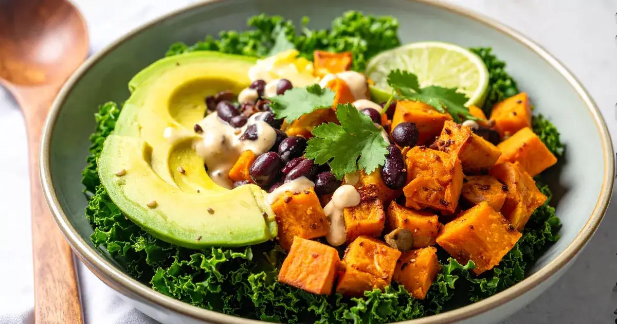 Herzhafte Süßkartoffel-Bohnen-Pfanne mit Avocado, Grünkohl und Limetten-Tahini-Dressing in einer rustikalen Schale.