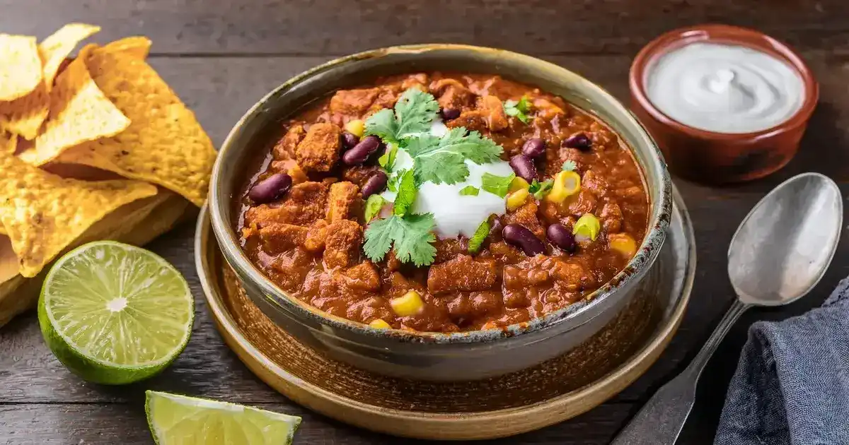 Würziges Tempeh Chili sin Carne mit Bohnen, Paprika und Avocado-Topping in einer Schale serviert.
