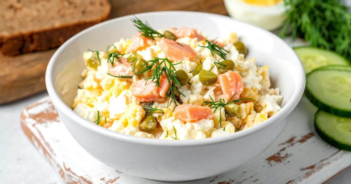 Proteinreicher Eiersalat mit Hüttenkäse, Räucherlachs, Dill und Cornichons in einer weißen Schale serviert.