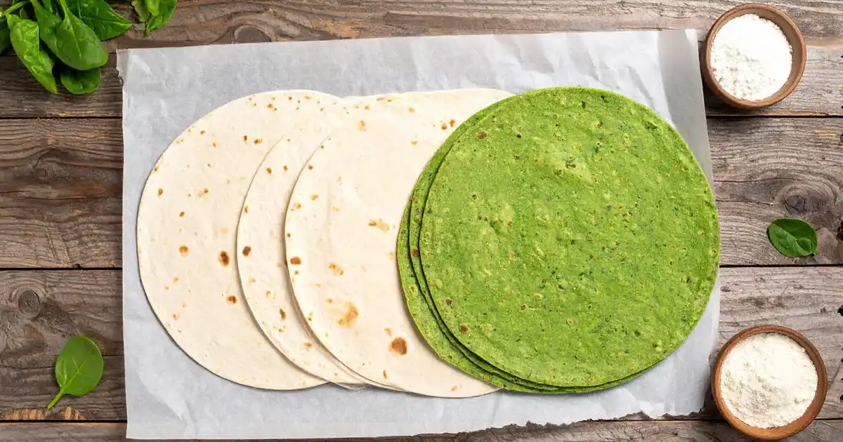 Klassische und grüne Protein-Wraps ungefüllt flach ausgelegt, dekoriert mit Spinat und Zutaten