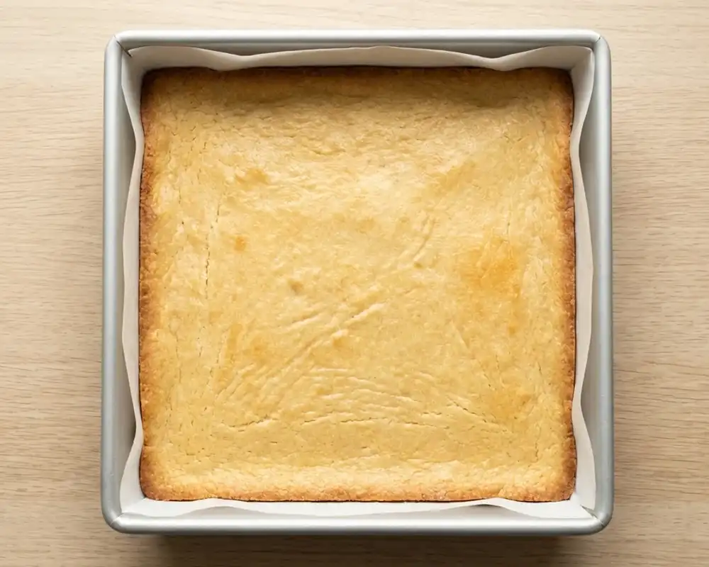 Vorgebackener Mandelboden in quadratischer Backform für Keto Cheesecake Bars