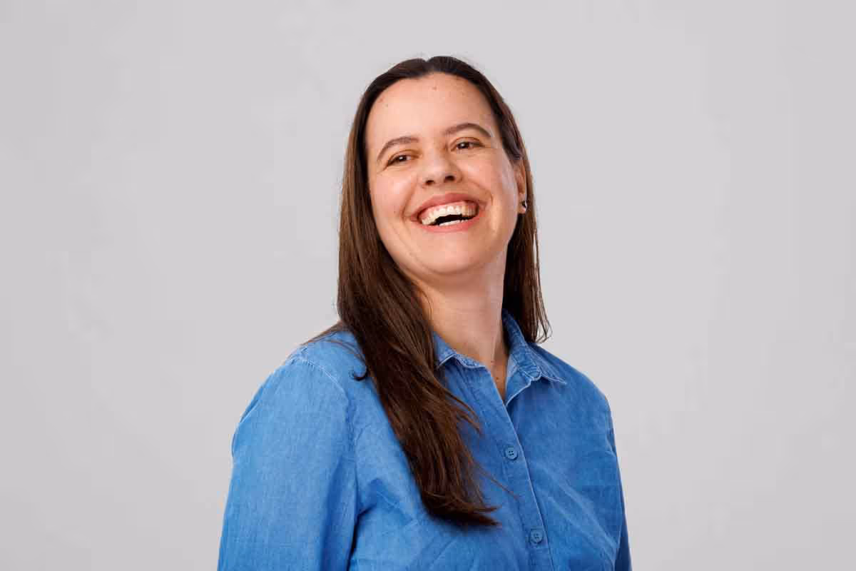 Banxware team member portrait Kassi, dark hair, blue shirt, laughing