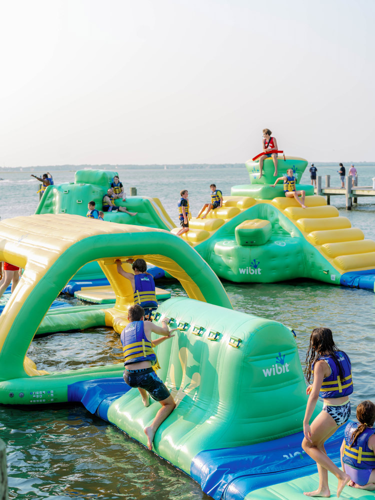 Kids in life vests climbing and sliding on the inflatable Aqua Park at Ocean City Boathouse Marina
