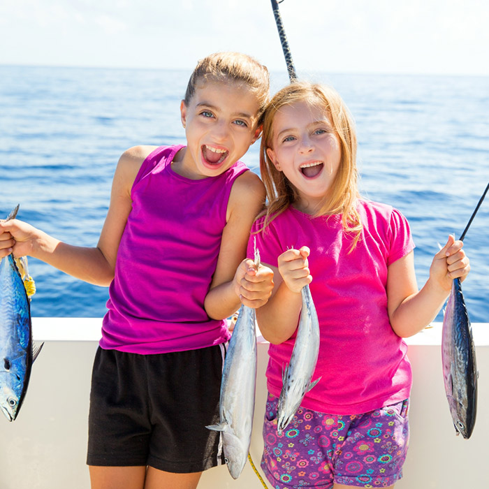 Two smiling kids holding freshly caught fish on a Shark Bait family fishing charter in Ocean City, NJ