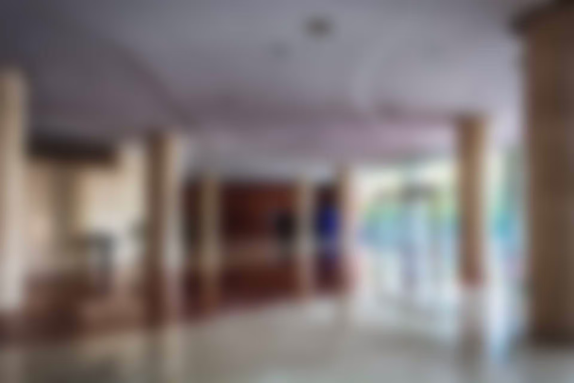 A large, empty hotel lobby with polished floors and bright natural light coming through glass doors.