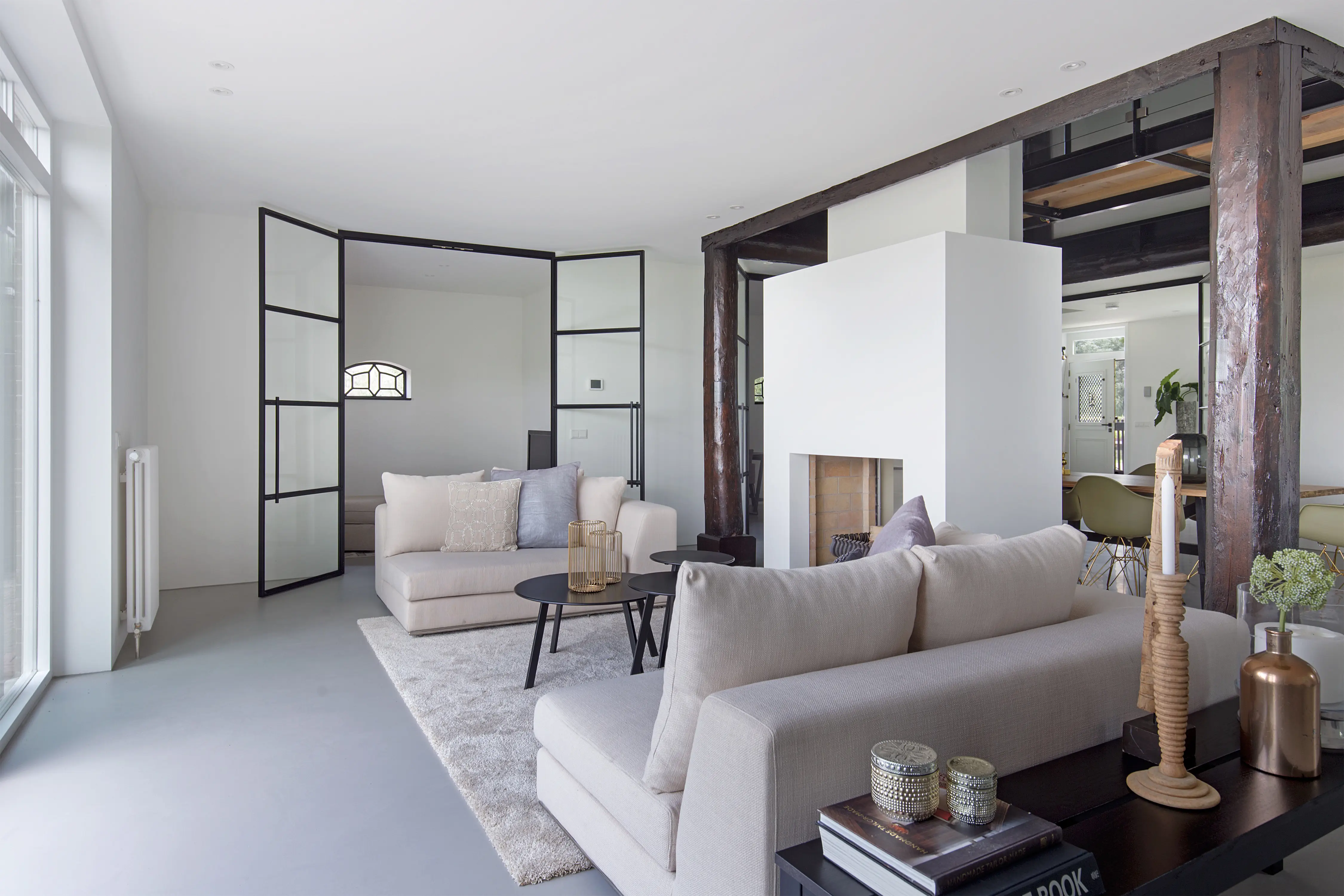 De woonkamer met moderne kenmerken van hoge glazen deuren in combinatie met traditionele accenten van een gerenoveerde boerderij.