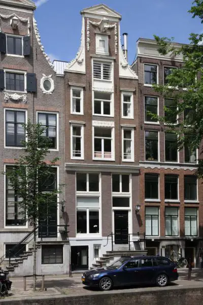 Gerestaureerd historisch grachtenpand in Amsterdam met een karakteristieke klokgevel, sierlijke ornamenten en grote ramen. De klassieke architectuur weerspiegelt de authentieke stijl van de Amsterdamse grachtengordel.