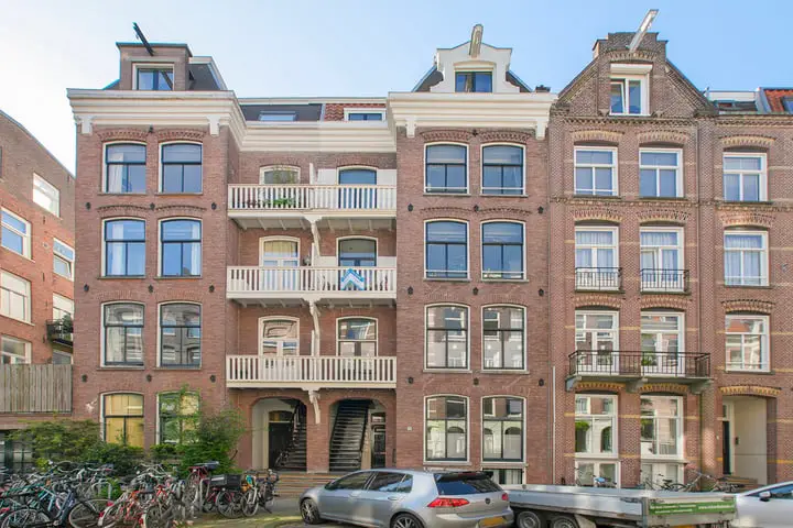 Gerestaureerd historisch pand met vernieuwde gevel en karakteristieke balkons in een stadsomgeving.