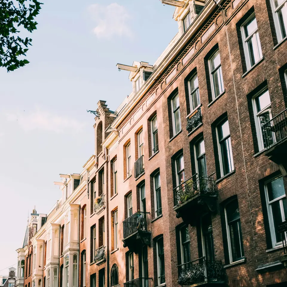 Interieur van een woningaanbouw in aanbouw met een grote witte schuifpui en zakken cement op een betonnen vloer.