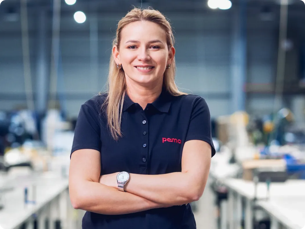 Eine Mitarbeitern steht mit verschränkten Armen und selbstbewusstem Blick in einer der Produktionshallen