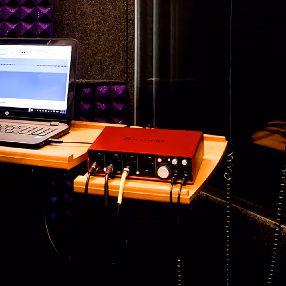 Focusrite audio interface connected to laptop inside a WhisperRoom vocal booth.