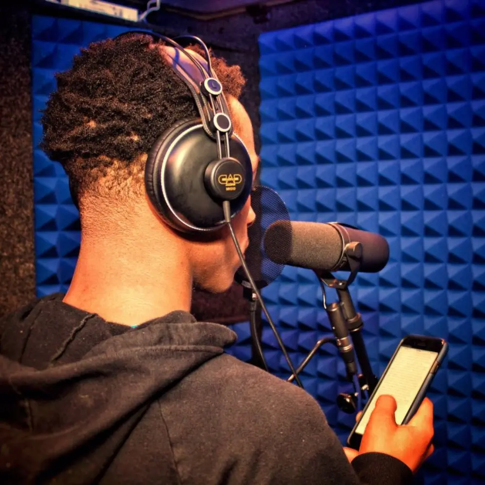 Voice over artist wearing closed-back studio headphones inside a WhisperRoom.