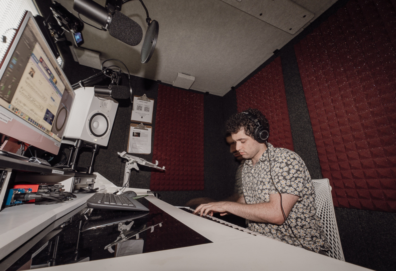 Musician recording on keyboard inside WhisperRoom 7296 S sound booth with acoustic treatment and studio setup