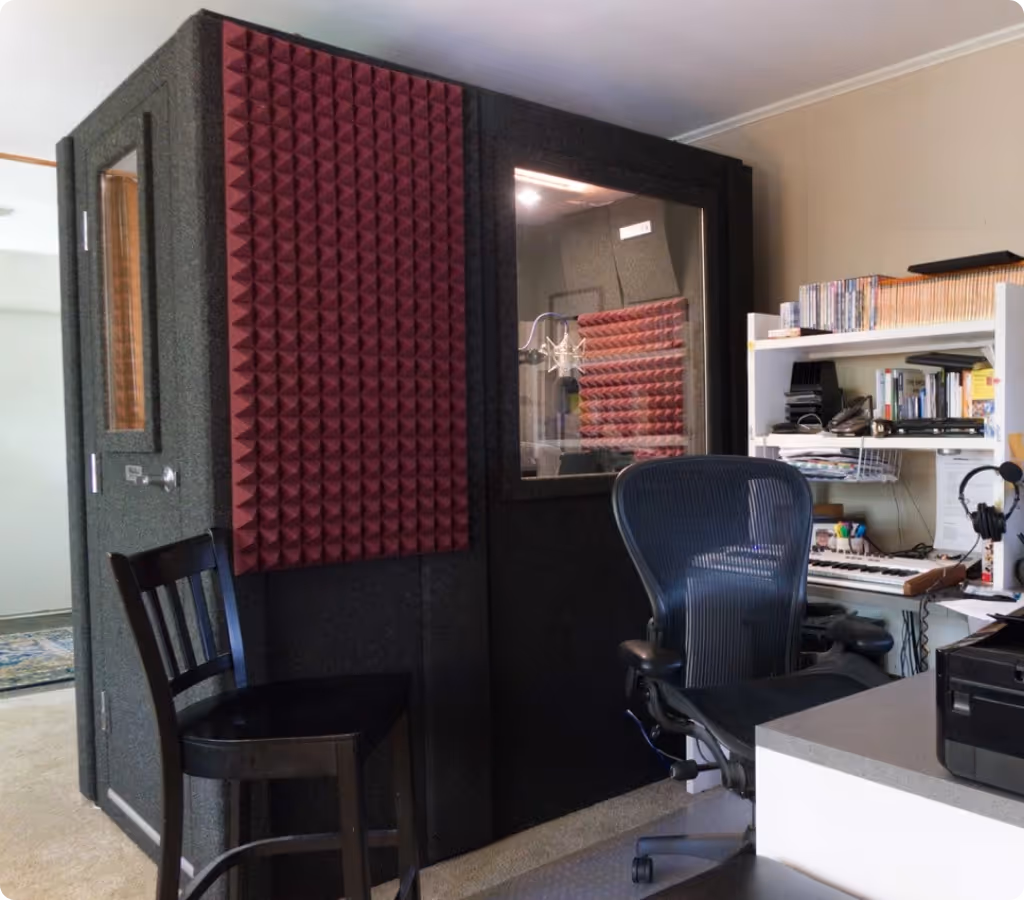 Exterior view of a WhisperRoom booth showing its footprint, window, and acoustic treatment panels in a home studio.