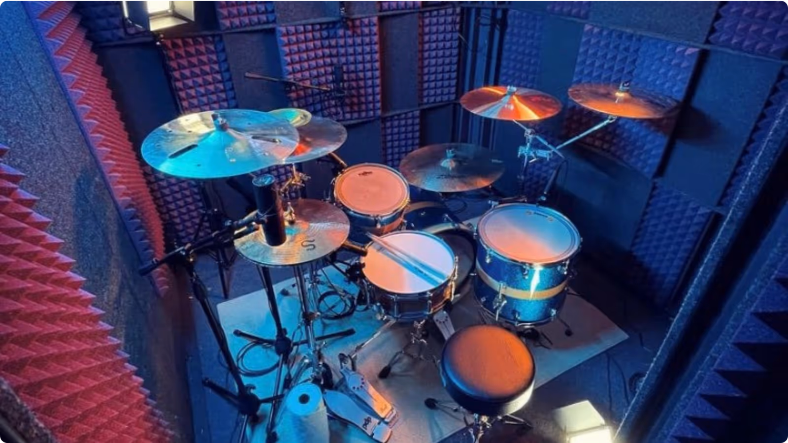 Professional drum recording setup inside a WhisperRoom booth with double-wall isolation, LED lighting, and full acoustic treatment.