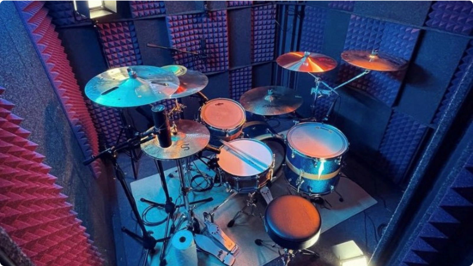 Professional drum recording setup inside a WhisperRoom booth with double-wall isolation, LED lighting, and full acoustic treatment.