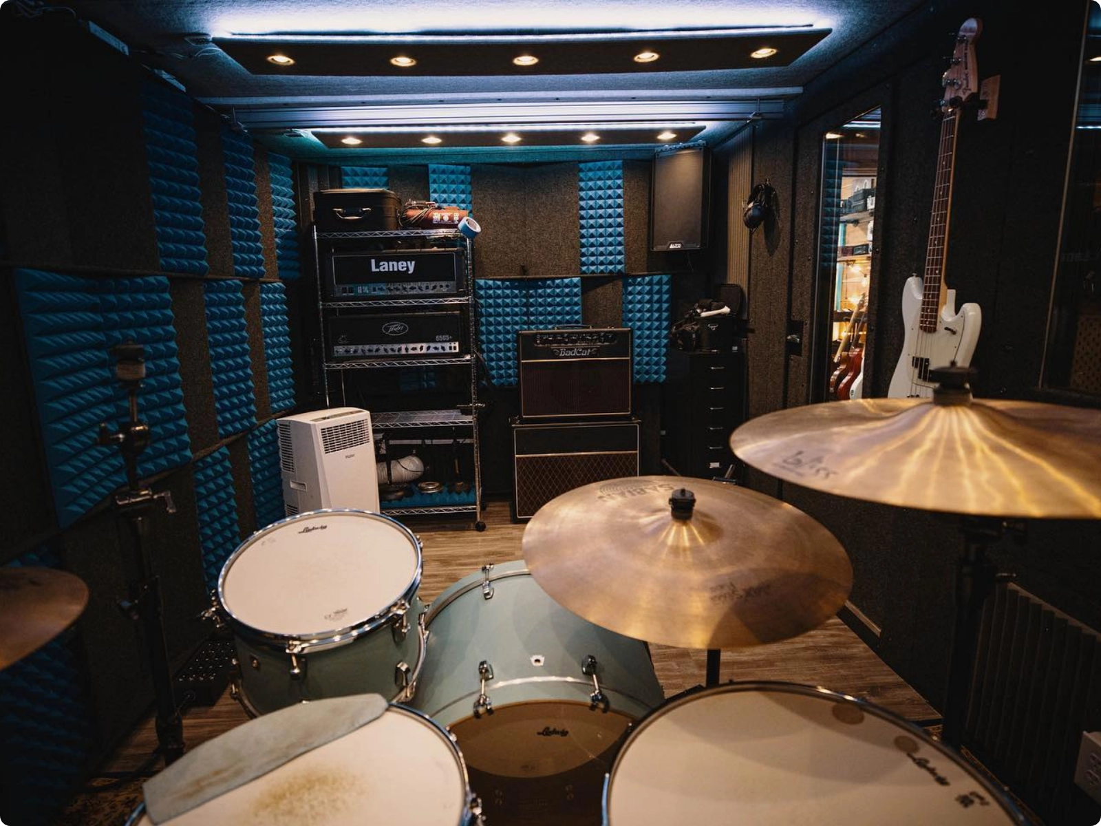 Drum setup inside a WhisperRoom booth with acoustic treatment and overhead ventilation.