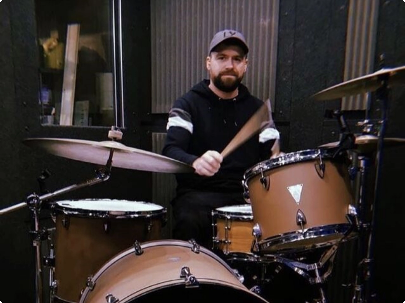 Drummer inside a WhisperRoom booth with clean modular wall panels.