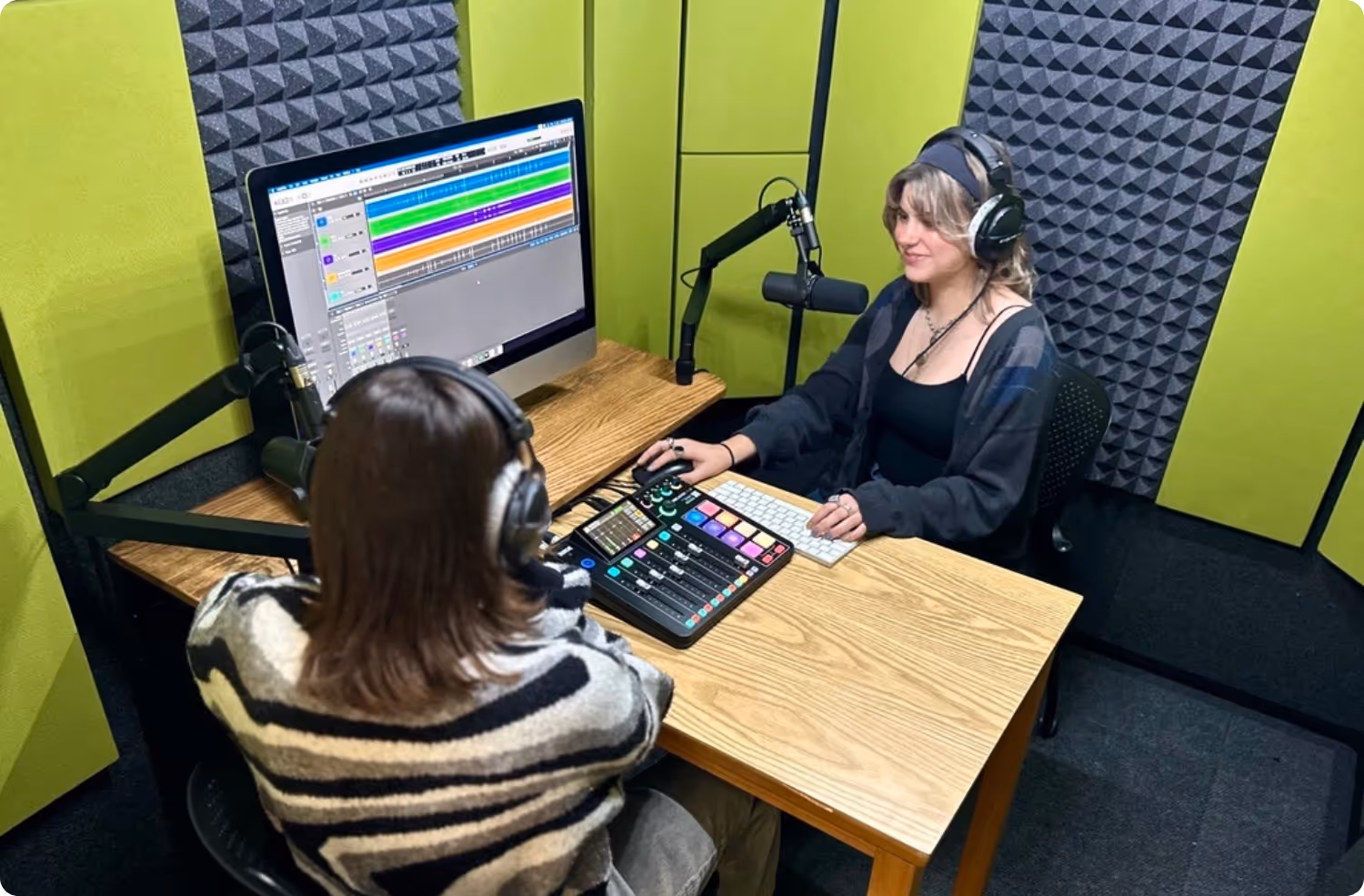 Podcast recording setup inside a WhisperRoom booth featuring Green Apple Audimute fabric acoustic panels