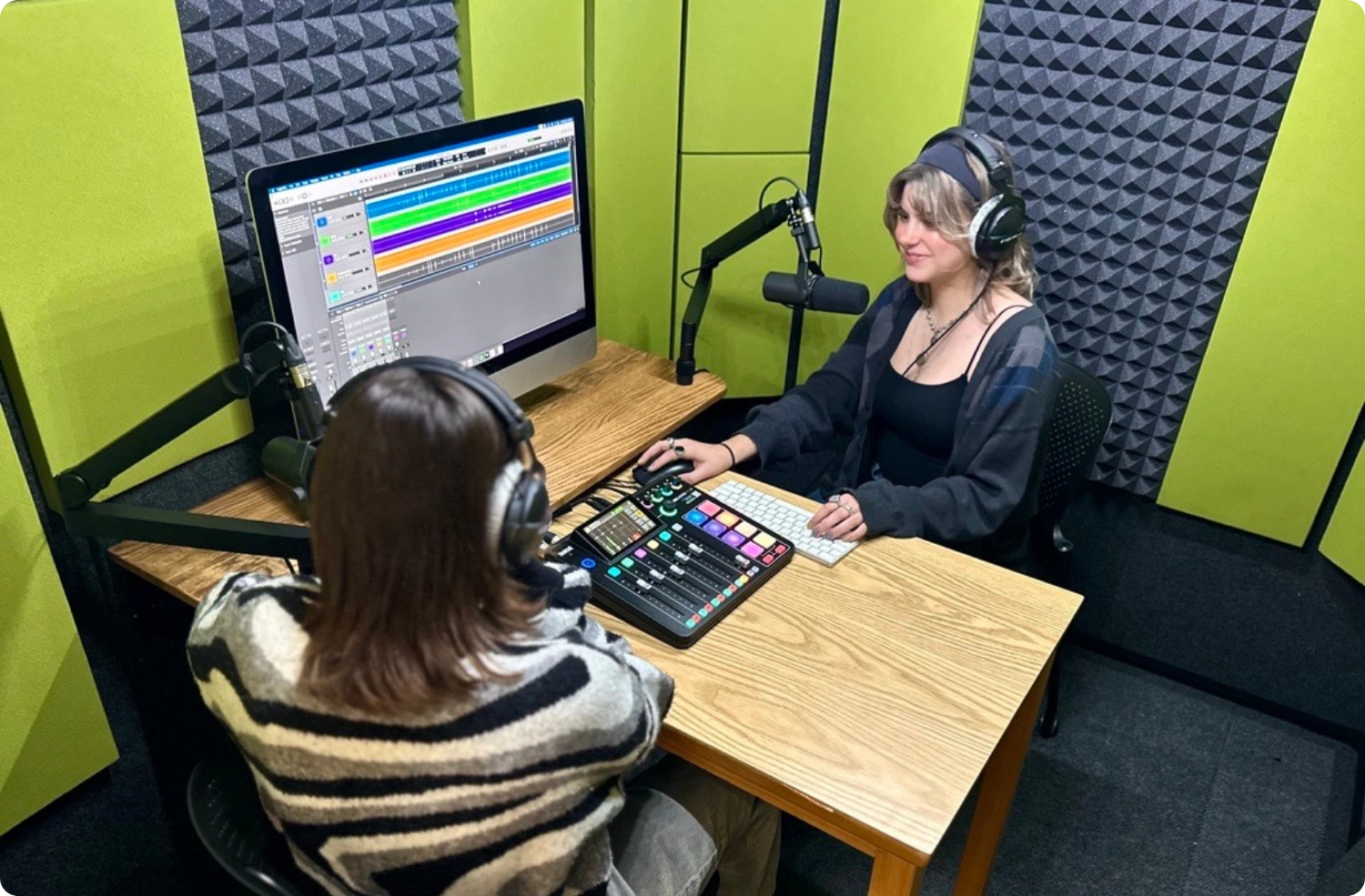 Podcast recording setup inside a WhisperRoom booth featuring Green Apple Audimute fabric acoustic panels