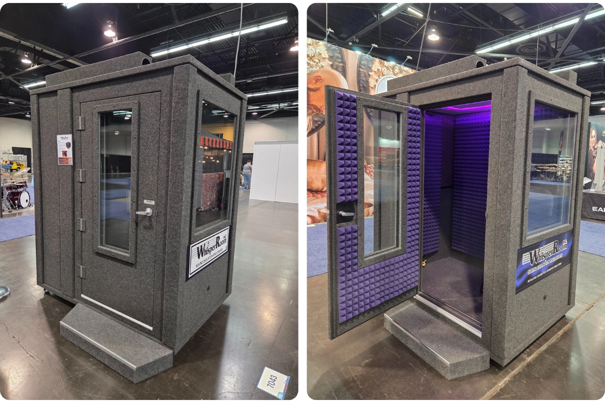 WhisperRoom sound isolation booth on the NAMM Show floor, shown closed and open to demonstrate exterior placement and interior sound treatment