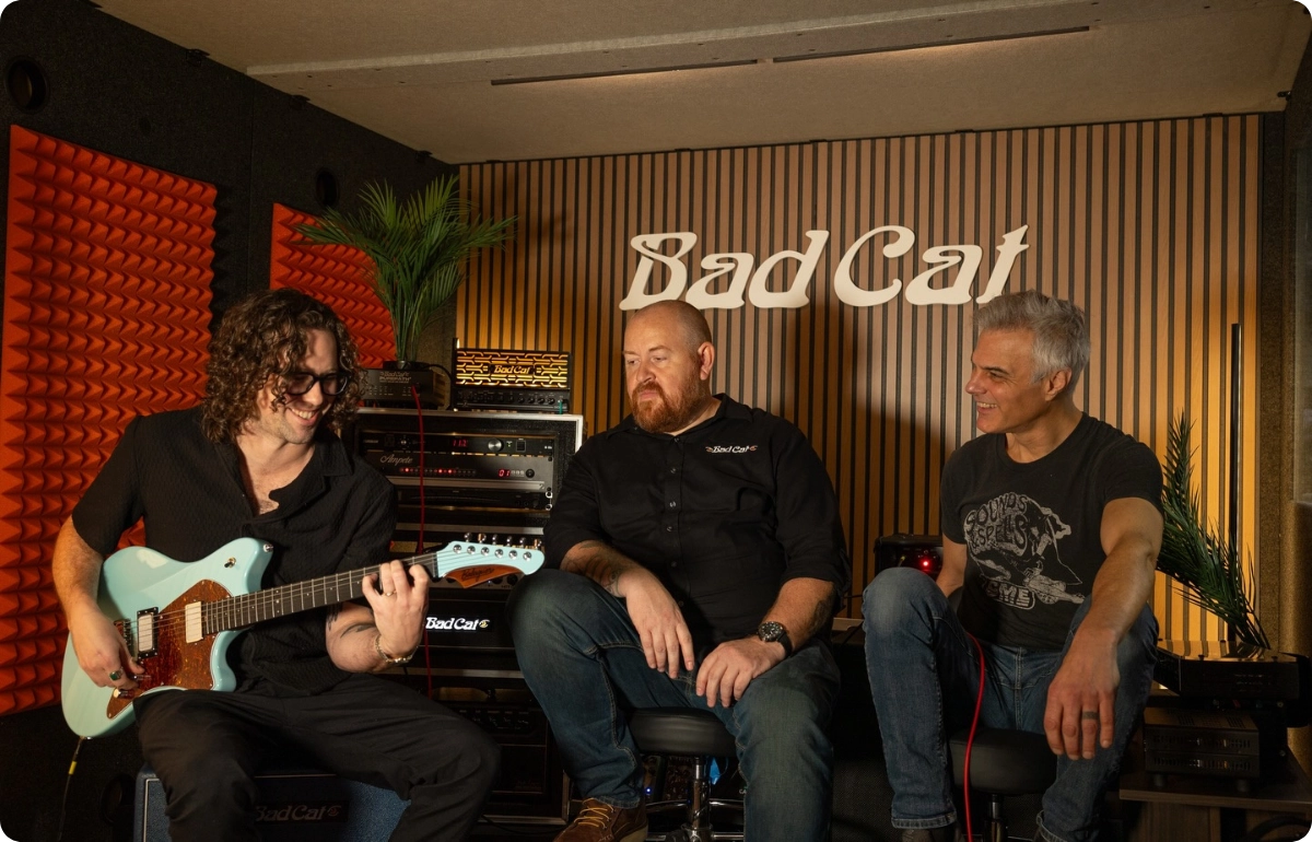Musicians demonstrating Bad Cat amplifiers inside a WhisperRoom sound isolation booth at a trade show