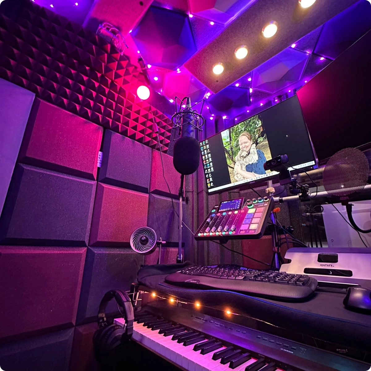 A look inside a creator recording booth setup with a broadcast mic, monitor, acoustic treatment, lighting, and other recording equipment