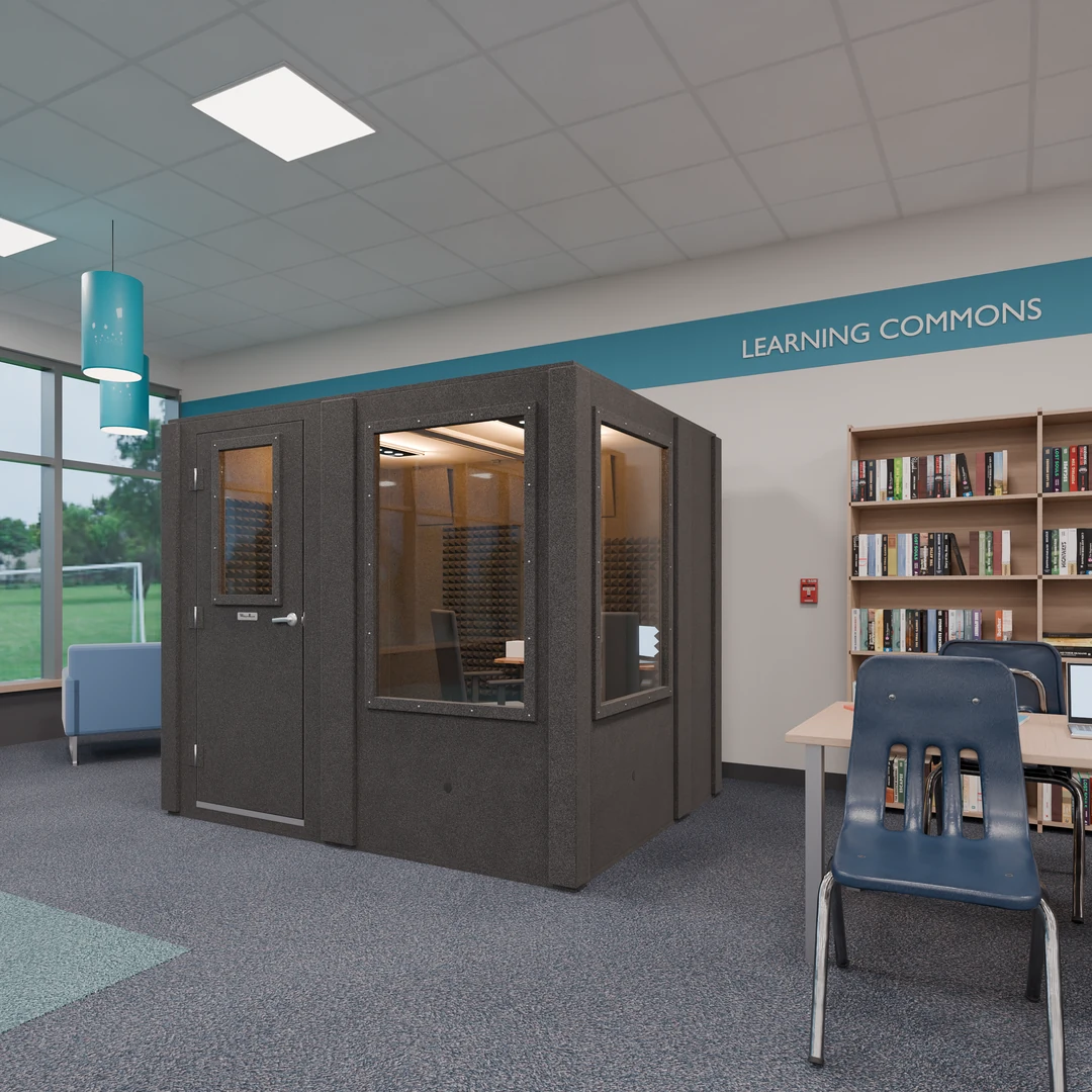 Meeting Booth in a school library under a Learning Commons sign, a windowed meeting pod beside the bookshelves