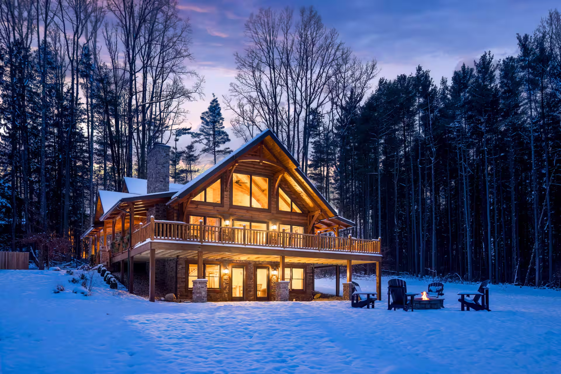 Hochstetler Log Home Exterior snow covered at night with lights glowing