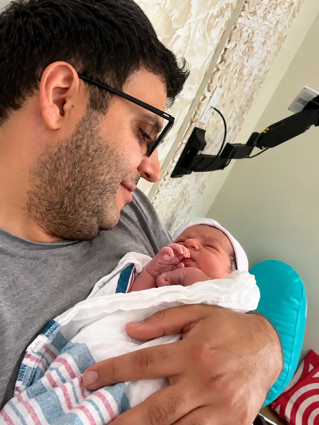 Parent holding a sleeping newborn swaddled in a hospital blanket