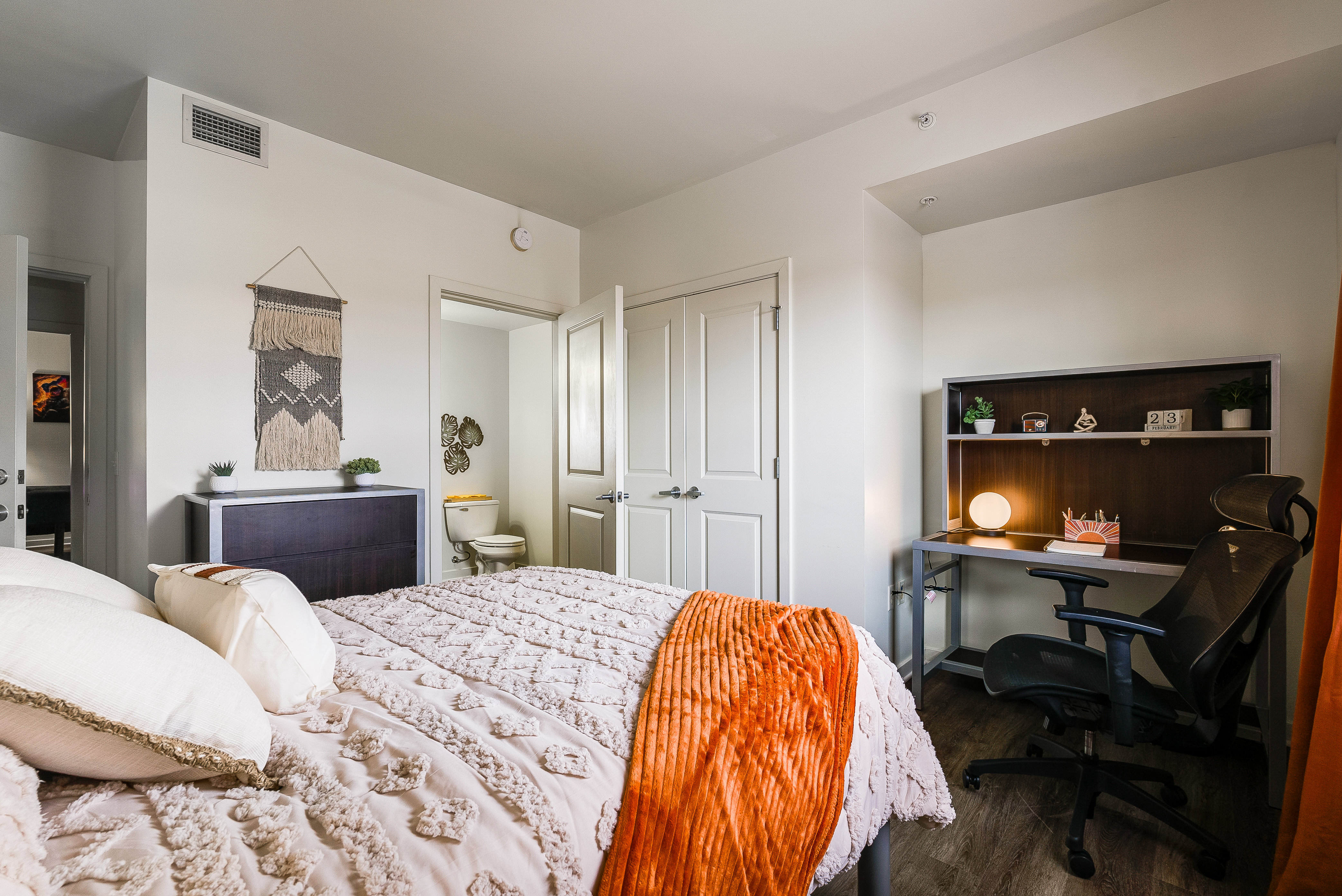 Bedroom with bed and desk with chair and view into bathroom
