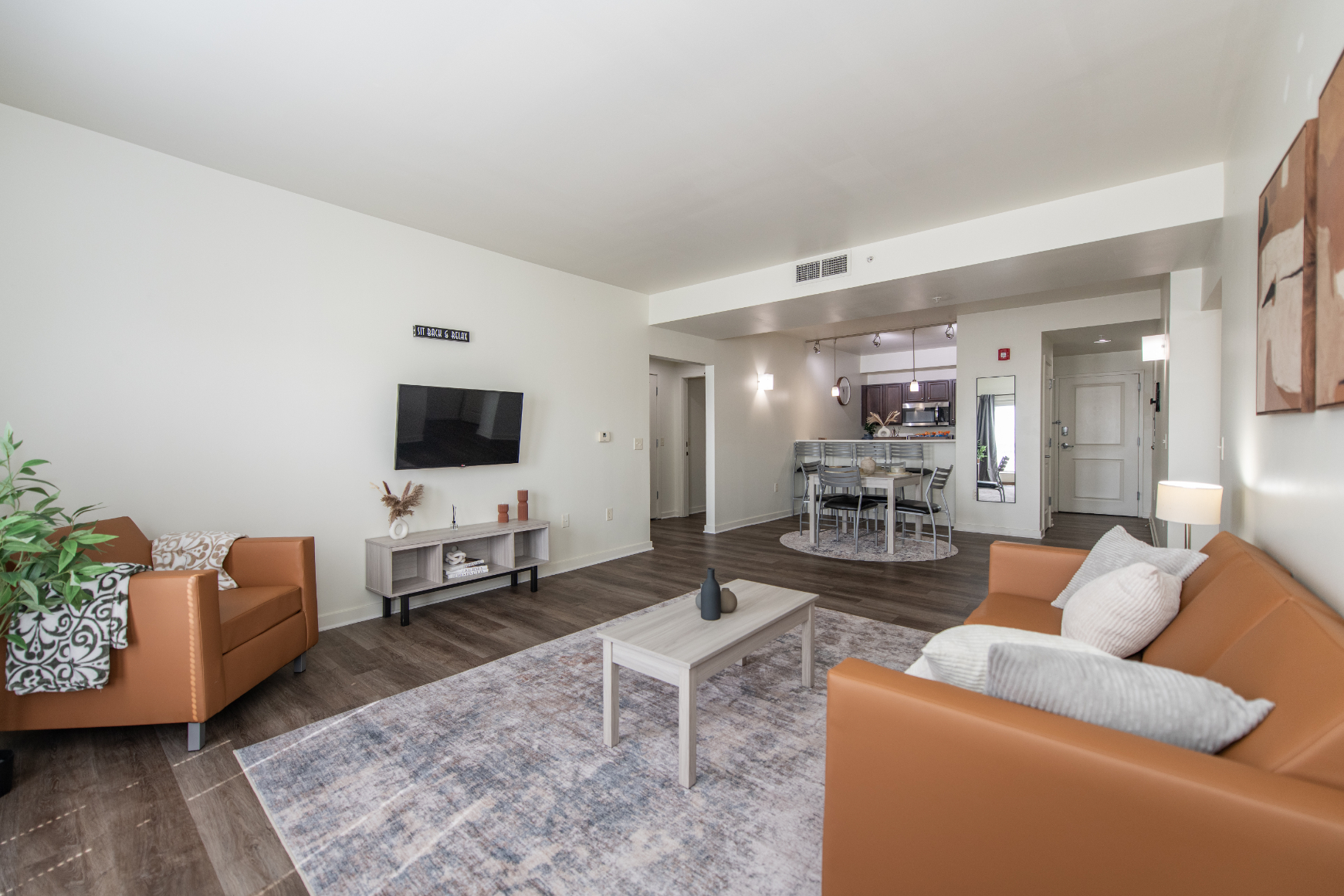 Living room with sofa, rug, coffee table, and tv and view of balcony doors with curtains