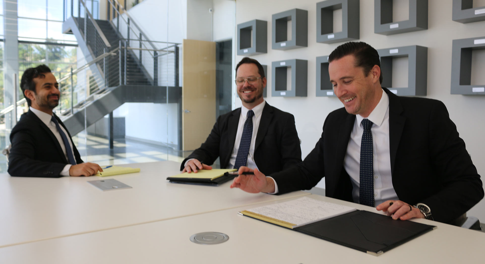 3 men in suits sitting a table talking