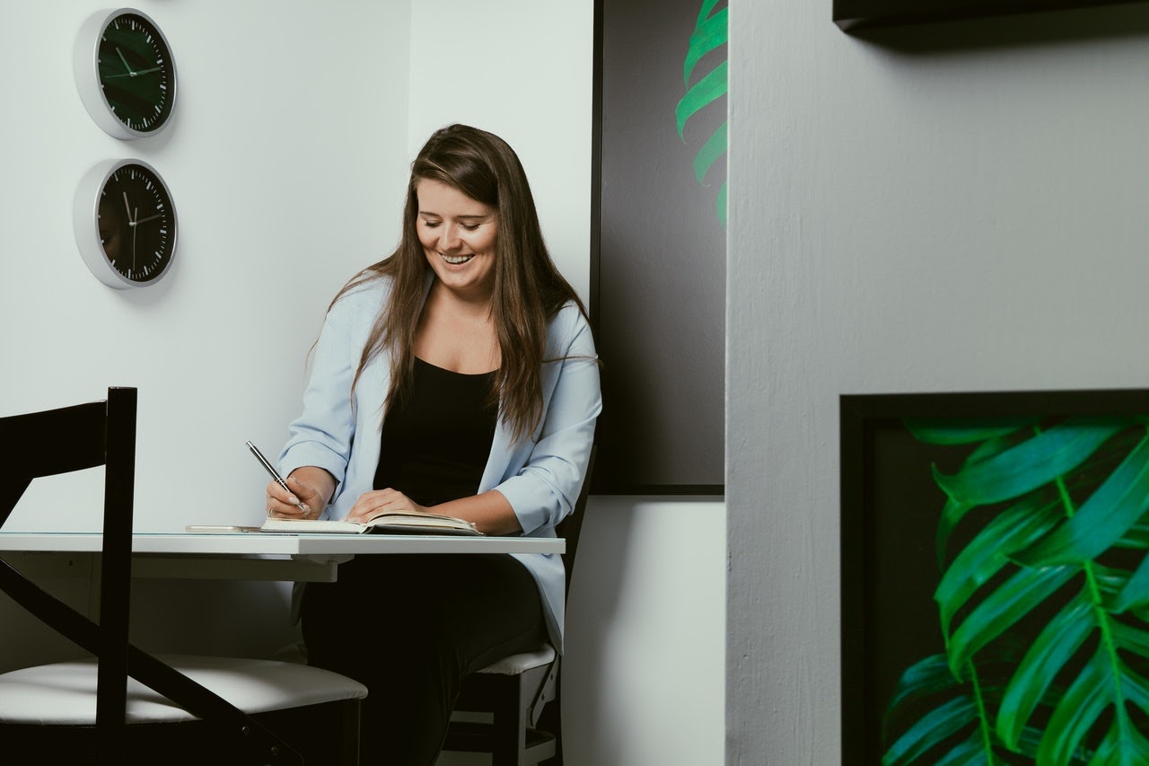 a woman writing in a notebook brainstorming blog ideas